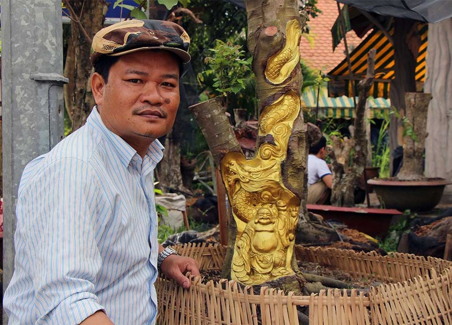 Anh Trần Quốc Việt bên tượng Phật Di Lặc được khắc tinh xảo trên cây khế còn sống