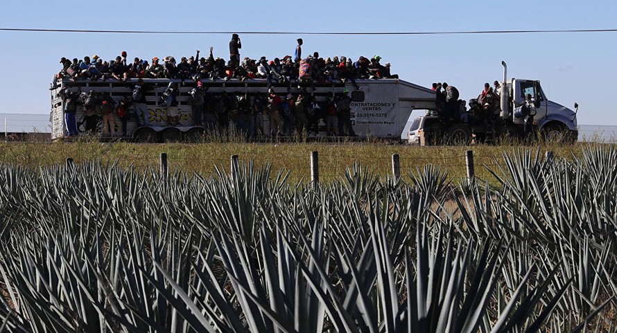 Những người di cư Trung Mỹ trên một chiếc xe tải di chuyển qua các trang trại để đến biên giới Mỹ. Ảnh: AP
