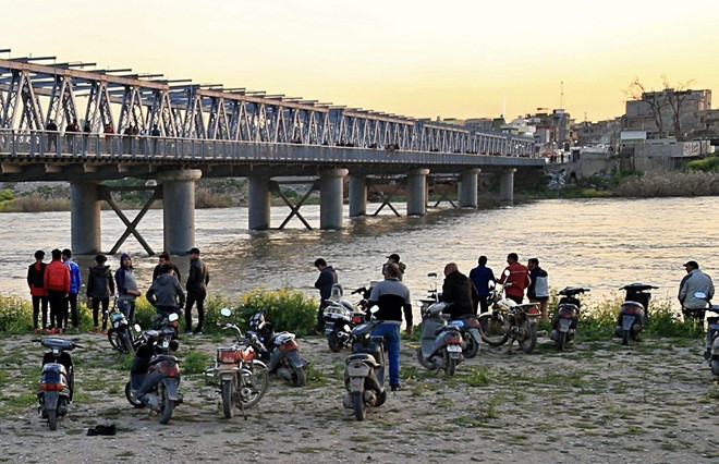 Người dân và người nhà nạn nhân chờ đợi trên bờ sông Tigris sau vụ tai nạn chìm phà. Ảnh: AP.