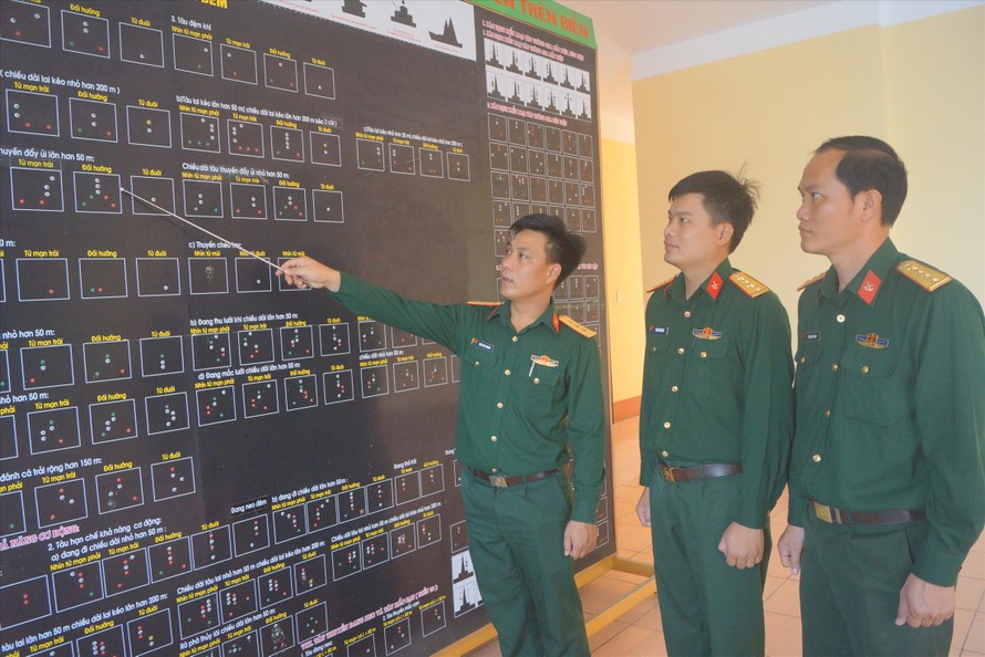 Thượng úy Trần Văn Vượng hướng dẫn đồng đội trên bảng tín hiệu nhận dạng tàu thuyền trên biển ẢNH: N.S