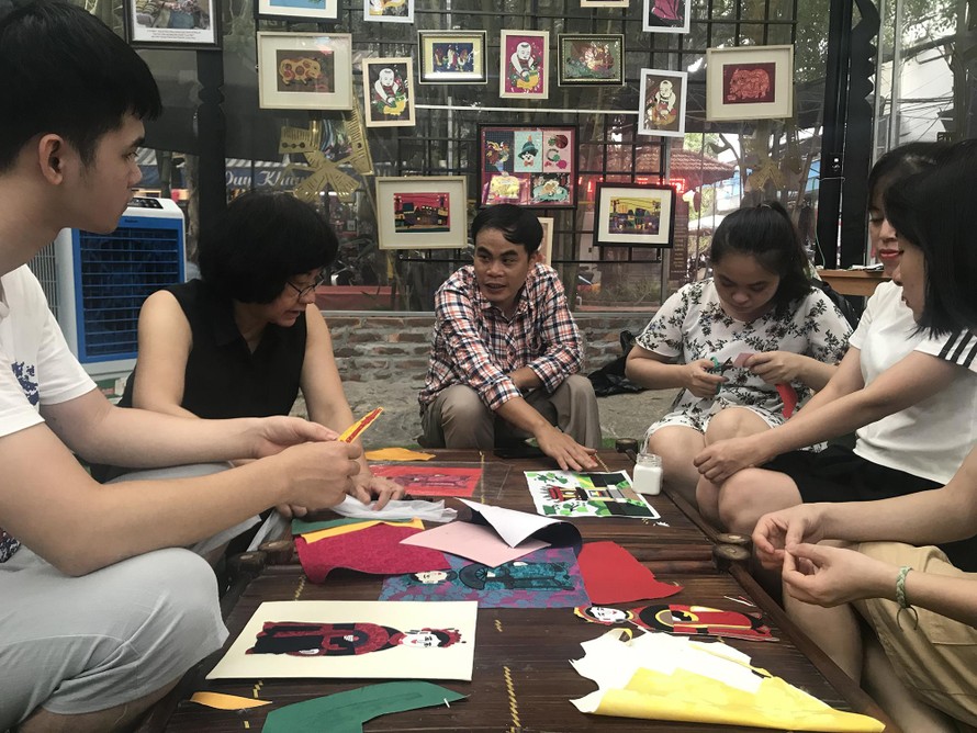 Anh Lê Việt Cường (áo sọc) và họa sĩ Đặng Thị Khuê (áo đen) hướng dẫn các bạn trẻ khuyết tật làm tranh ảnh Nhã Khanh