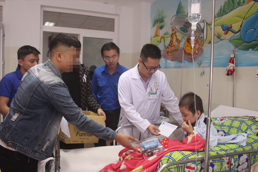 N.T.L (bên trái) – thành viên trong đoàn tình nguyện đặc biệt trao quà cho một bệnh nhi đang điều trị ở khoa Nội 3 – Bệnh viện Ung bướu Đà NẵngẢnh: Giang Thanh
