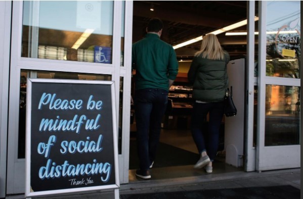 Tấm biển mới dựng trước cửa hàng ở Seattle, bang Washington có dòng chữ: Chú ý giữ khoảng cách ảnh: REUTERS