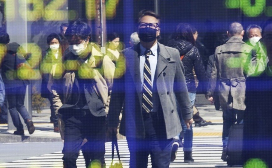 Hình ảnh người dân đeo khẩu trang được phản chiếu trên bảng điện tử của một công ty chứng khoán tại Tokyo ngày 18/3ảnh: AP