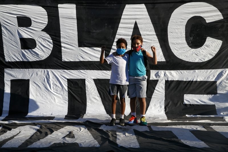 Hai cậu bé da màu đứng trước khẩu hiệu của người biểu tình căng ngoài công viên Lafayette ngày 7/6Ảnh: AP