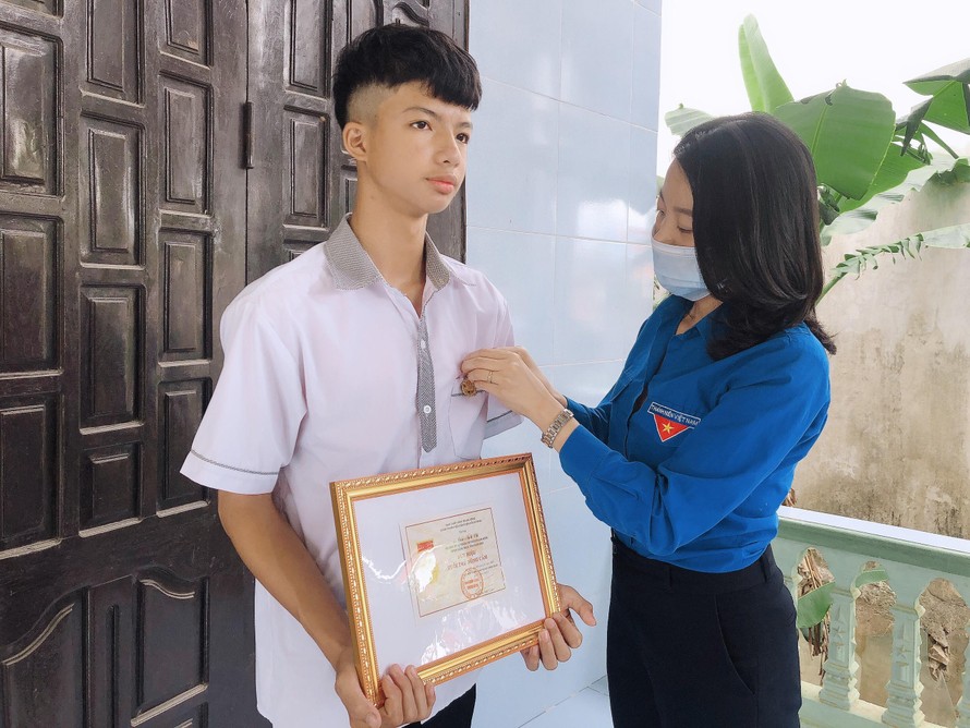 Chị Lê Thị Ngọc Hà, Phó Bí thư Tỉnh đoàn Quảng Bình thừa ủy quyền của BCH Trung ương Đoàn trao tặng Huy hiệu "Tuổi trẻ dũng cảm” cho học sinh Cao Anh Vũ.