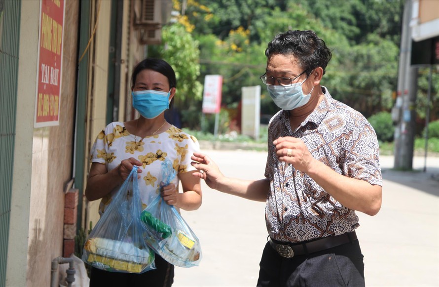 Ông Khoát, thành viên tổ COVID cộng đồng ở Tổ dân phố My Điền 1 thăm hỏi, động viên công nhân bị phong tỏa. Ảnh: Nguyễn Thắng