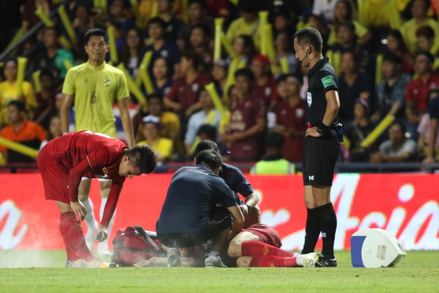 Trong lúc bác sỹ chăm sóc đồng đội bị phạm lỗi phải nằm sân, Quang Hải cũng tranh thủ xịt thuốc giảm đau sau những pha vào bóng quyết liệt của cầu thủ Thái Lan. Ảnh: Hữu Phạm