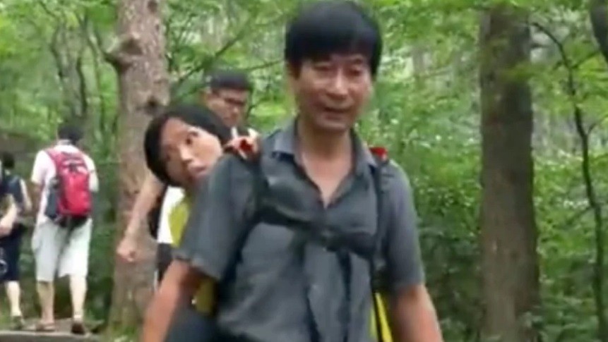 Người chồng cõng vợ lên núi Hoàng Sơn, một di sản thế giới được UNESCO công nhận. Ảnh chụp từ video.