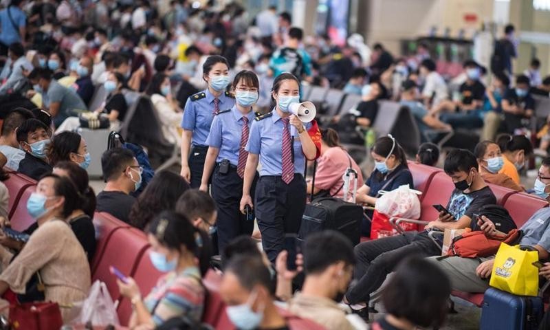 Các nhân viên tại ga Hán Khẩu, tỉnh Vũ Hán, Trung Quốc nhắc nhở hành khách tuân thủ các quy định về phòng, chống dịch COVID-19 hôm 21/9.