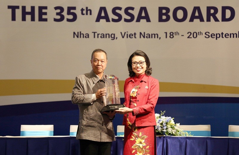 Chủ tịch ASSA 34 Suradej Waleeittikul (trái) chuyển giao biểu trưng và tài liệu cho Chủ tịch ASSA 35 Nguyễn Thị Minh - Thứ trưởng, Tổng Giám đốc BHXH Việt Nam (phải).