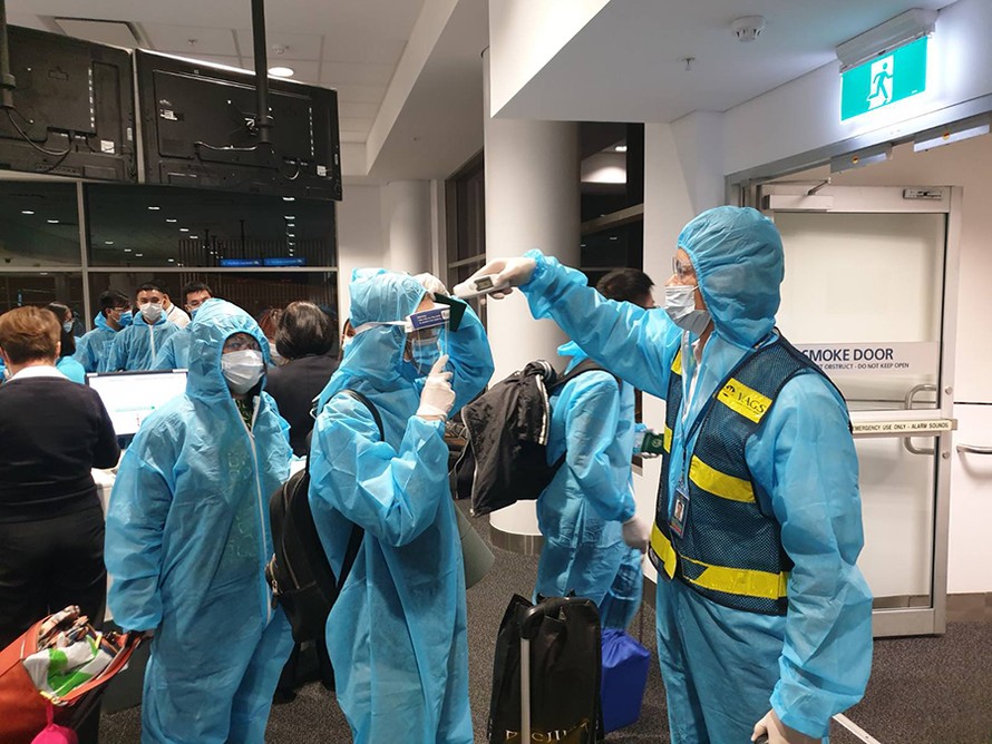 Đo thân nhiệt hành khách trước khi lên máy bay tại Úc, toàn bộ hành khách và tổ bay đều mặc trang phục bảo hộ y tế.