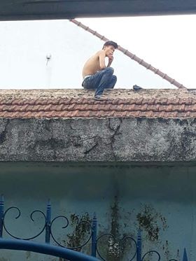 Nam thanh niên nghi ngáo đá đột nhiên leo mái nhà, liên tục la hét, dọa đâm bụng mình. Ảnh: Dân Việt