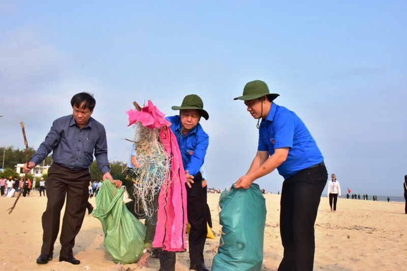 Chủ tịch Phan Ngọc Thọ (giữa) hăn hái gom nhặt rác, góp phần làm sạch môi trường bãi tắm Thuận An
