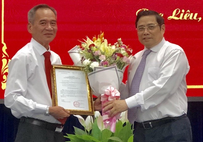 Ông Lữ Văn Hùng (trái) nhận quyết định và hoa chúc mừng của Trưởng ban Tổ chức Trung ương Phạm Minh Chính -Ảnh: Zing.vn