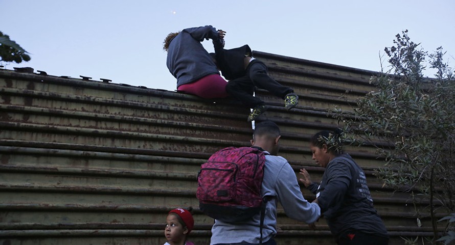 Những người di cư nhau vượt qua bức tường biên giới Mỹ từ Mexico. Ảnh: AP