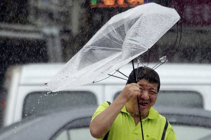 Một người đàn ông Đài Loan bị lật ô giữa cơn mưa bão. Ảnh AP