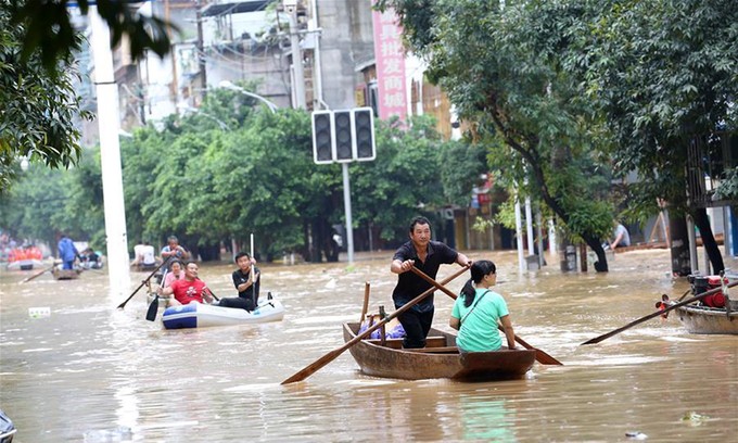 Lũ lụt dâng cao khiến người dân phải chèo thuyền đi lại ở huyện Dung Thủy, tỉnh Quảng Tây. Ảnh: Xinhua