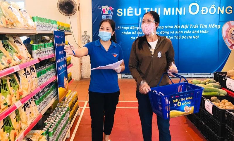 Tình nguyện viên hướng dẫn người dân chọn nhu yếu phẩm tại siêu thị 0 đồng thị xã Sơn Tây.