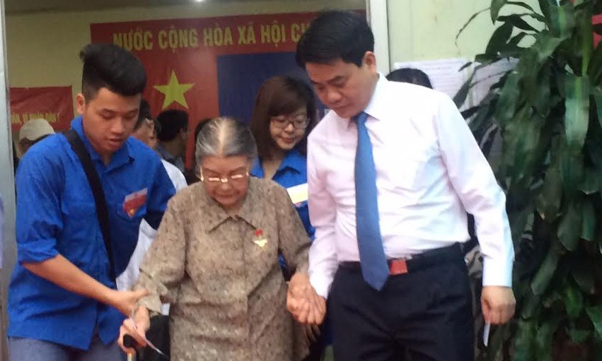 Chủ tịch UBND thành phố Hà Nội Nguyễn Đức Chung hỗ trợ một cử tri cao tuổi tại điểm bỏ phiếu bỏ phiếu số 3 phường Trung Liệt, quận Đống Đa, Hà Nội. Ảnh: Tú Anh.