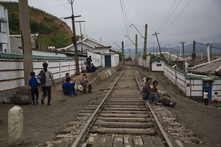 Hình ảnh người dân ngồi nghỉ bên cạnh một đường ray tàu hỏa chạy qua thị trấn nhỏ ở tỉnh Bắc Hamgyong, Triều Tiên qua góc máy phóng viên AP cho thấy cuộc sống ở những khu vực xa xôi của Triều Tiên.