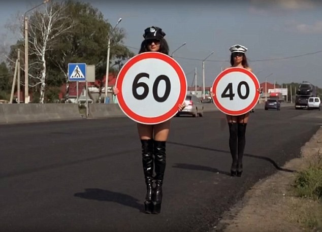 Các cô gái cầm biển báo hạn chế tốc độ trên đường.