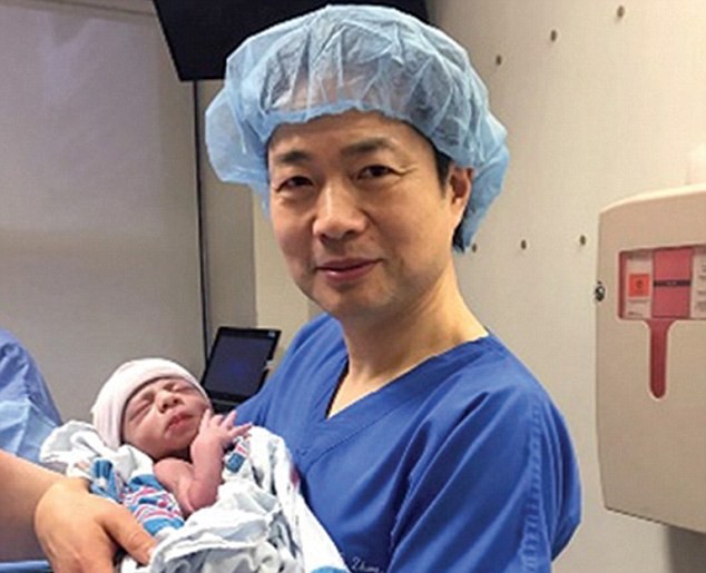 Bác sĩ Zhang ôm trên tay em bé có 3 bố mẹ đầu tiên trên thế giới.