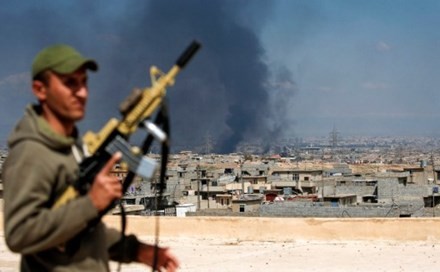 Một binh sỹ Iraq đứng trên nóc một tòa nhà ở tây Mosul, phía sau khói đạn bốc lên mù mịt. Ảnh: AFP
