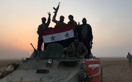 Quân đội Syria cầm quốc kì ăn mừng sau khi tiến vào thị trấn Albu Kamal hồi đầu tháng 11. Ảnh: AFP
