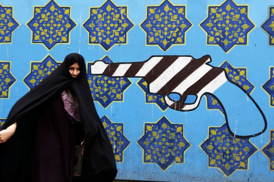 Một phụ nữ Iran đi qua bức tranh trên tường Đại sứ quán cũ của Mỹ tại Tehran. Ảnh: AFP