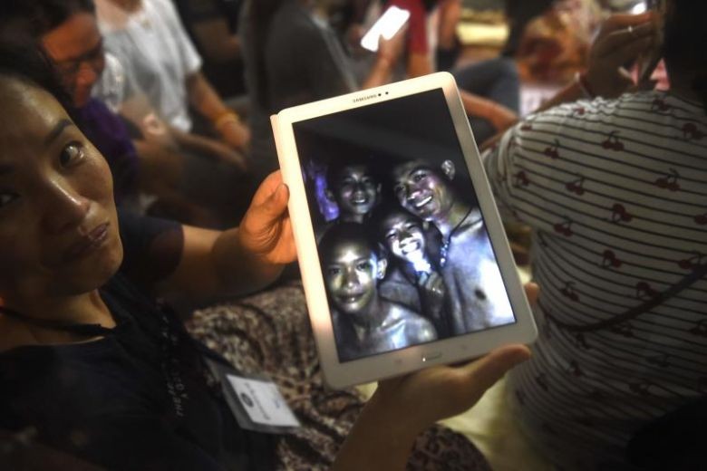 Thân nhân cầm trên tay bức ảnh được chụp trước khi các nam sinh mất tích. Ảnh: AFP