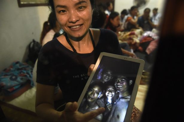 Người thân cầm ảnh các cầu thủ nhí của đội bóng Lợn Hoang. Ảnh: AFP