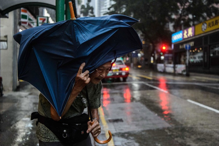 Một cụ bà che ô đứng đợi taxi tại Hồng Kông sáng 16/9. Ảnh: Getty