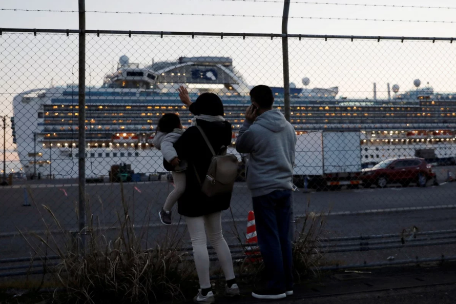 Thân nhân các hành khách mắc kẹt trên thuyền gọi điện và vẫy chào người nhà từ xa. Ảnh: Reuters