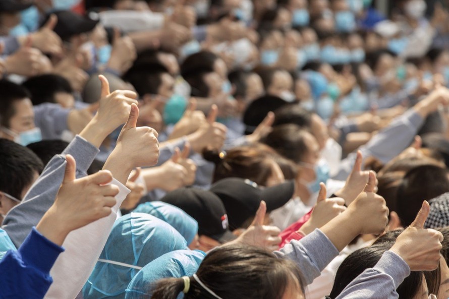 Các nhân viên y tế giơ ngón tay cái khi chụp ảnh lưu niệm trước khi rút khỏi Vũ Hán. Ảnh: Xinhua