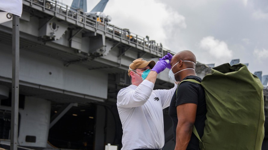 Thuỷ thủ tàu sân bay USS Roosevelt được kiểm tra thân nhiệt trước khi trở lại tàu. Ảnh: Reuters