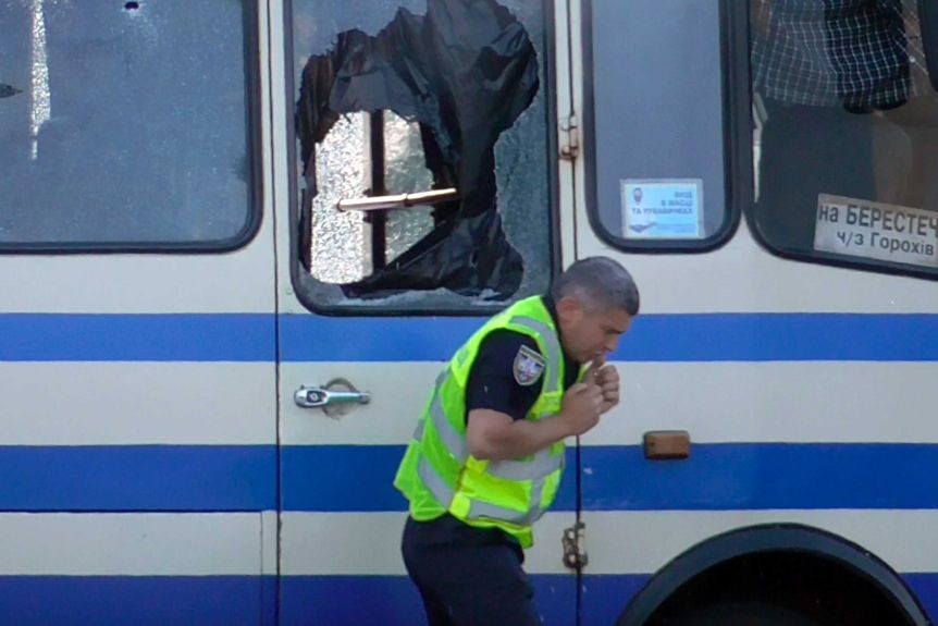 Một nhân viên an ninh đưa nước uống cho con tin trên xe buýt giật mình khi nghi phạm nổ súng. Ảnh: AP