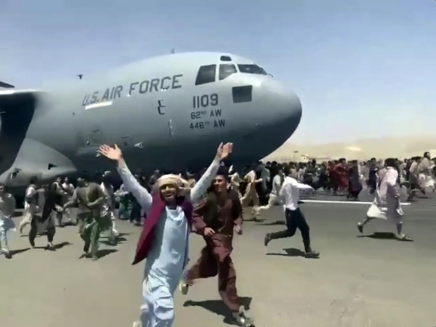 Người dân Afghanistan bám theo máy bay Mỹ đang cất cánh từ sân bay Kabul. Ảnh chụp màn hình