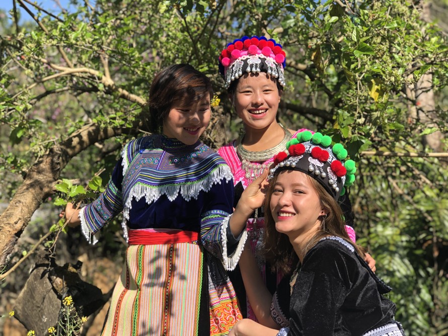 Ba chị em người Mông xúng xính váy áo truyền thống trước khi đi ăn Tết cộng đồng gần nhà. Ảnh: Thái An.