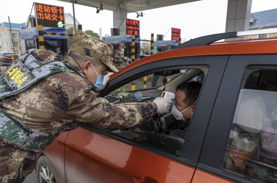 Một dân quân dùng nhiệt kế số để đo thân nhiệt tài xế tại trạm kiểm soát trên đường cao tốc ở Vũ Hán, Hồ Bắc hôm 23/1. Ảnh: AP. 