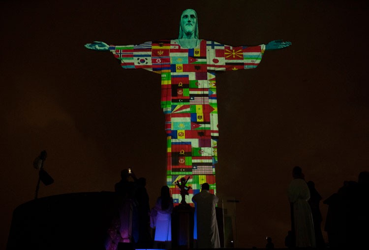 Tượng Chúa cứu thế ở Brazil ngày 18/3 được thắp sáng với hình quốc kỳ các nước đang có dịch Covid-19. Ảnh: AP.