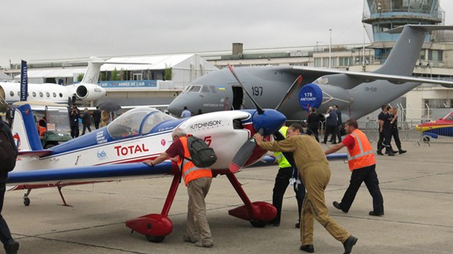 Các nhân viên đang đẩy máy bay nhào lộn AVA 432 MXS vào vị trí trưng bày sau khi biểu diễn.