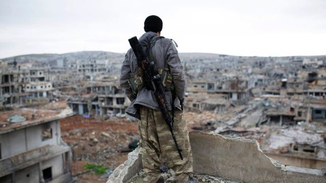 Tay súng người Kurd Syria nhìn cảnh tượng hoang tàn đổ nát tại thành phố chiến lược Kobane. Ảnh: AP