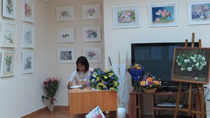 Một góc triển lãm tranh của Thúy Quỳnh và một khán giả đang viết những dòng cảm xúc về tranh của Thúy Quỳnh