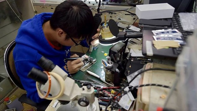 Một thợ sửa điện thoại tiến hành nâng cấp bộ nhớ trong iPhone. Nguồn: CCTV
