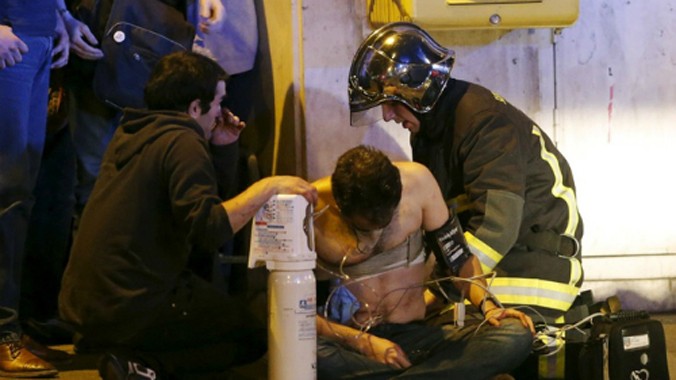 Lính cứu hoả Pháp hỗ trợ một người bị thương gần phòng hòa nhạc Bataclan. Ảnh: Reuters