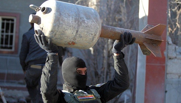 Một thành viên của Lực lượng chống khủng bố Iraq bê quả rocket "khủng" chế từ bình gas thu được trong kho vũ khí của IS tại thành phố Ramadi.