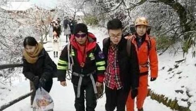 Hai nhân viên cứu hộ mang trang phục leo núi đang được các nhân chứng dẫn tới nơi du khách trẻ tuổi nhảy xuống vực. Ảnh: Chutian Metropolis News.
