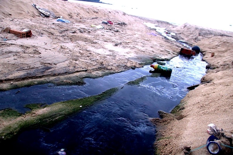 Nước thải đen ngòm chảy tràn xuống bãi biển Nam Ô. Ảnh: Nguyễn Thành