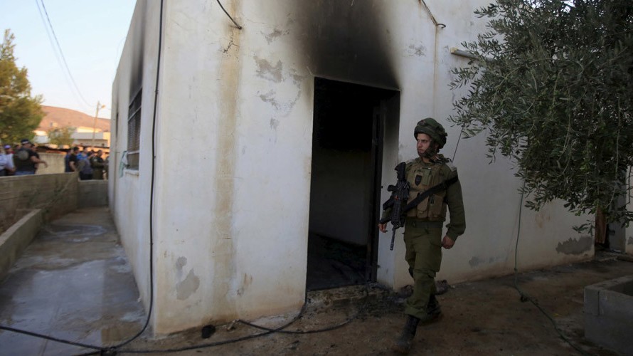 Một binh sỹ Israel đứng bên ngoài hiện trường vụ đốt phá khiến bé 18 tháng thiệt mạng